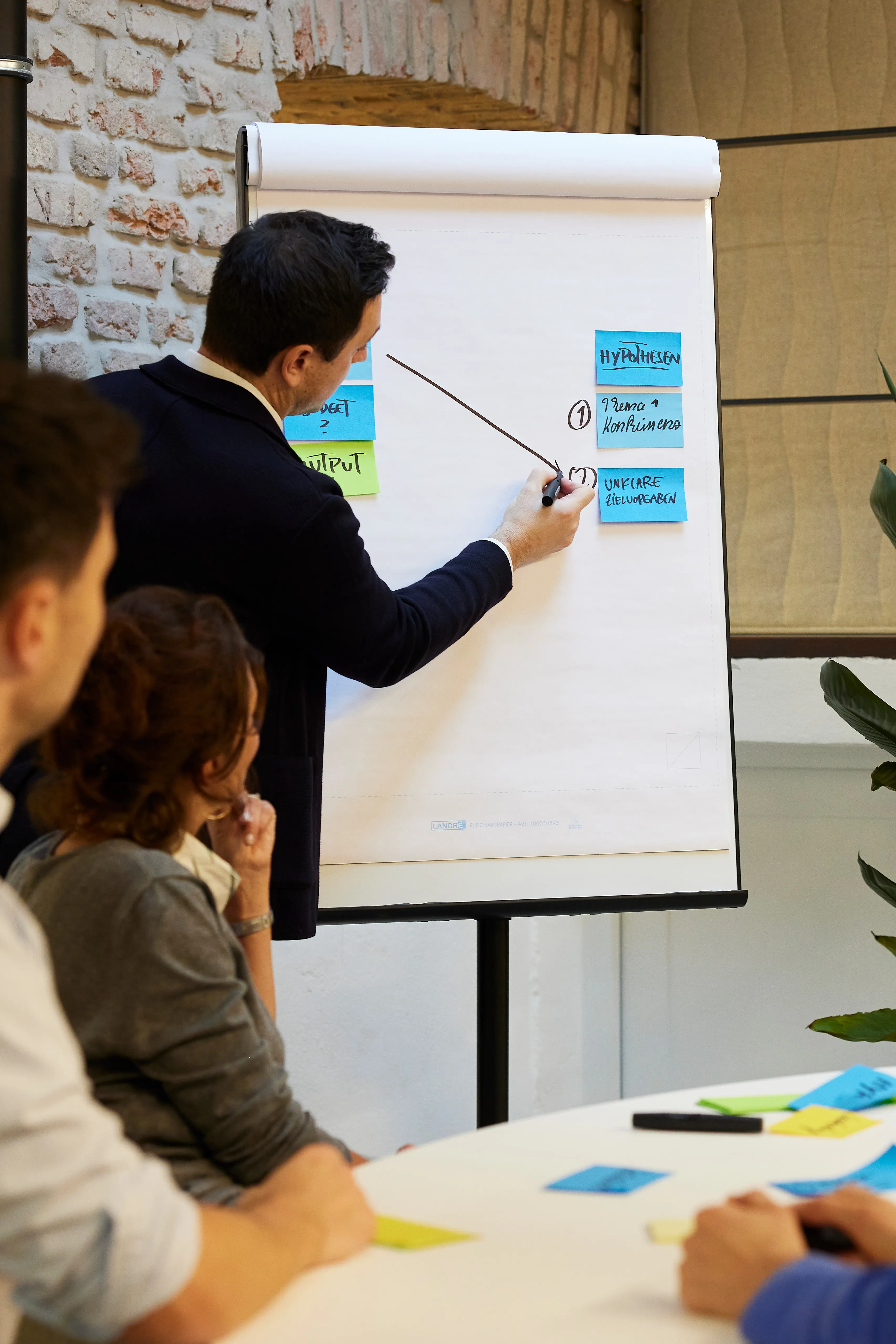 Berater erklärt Ziele am Flipchart in Organisationsentwicklungs-Workshop vor Team